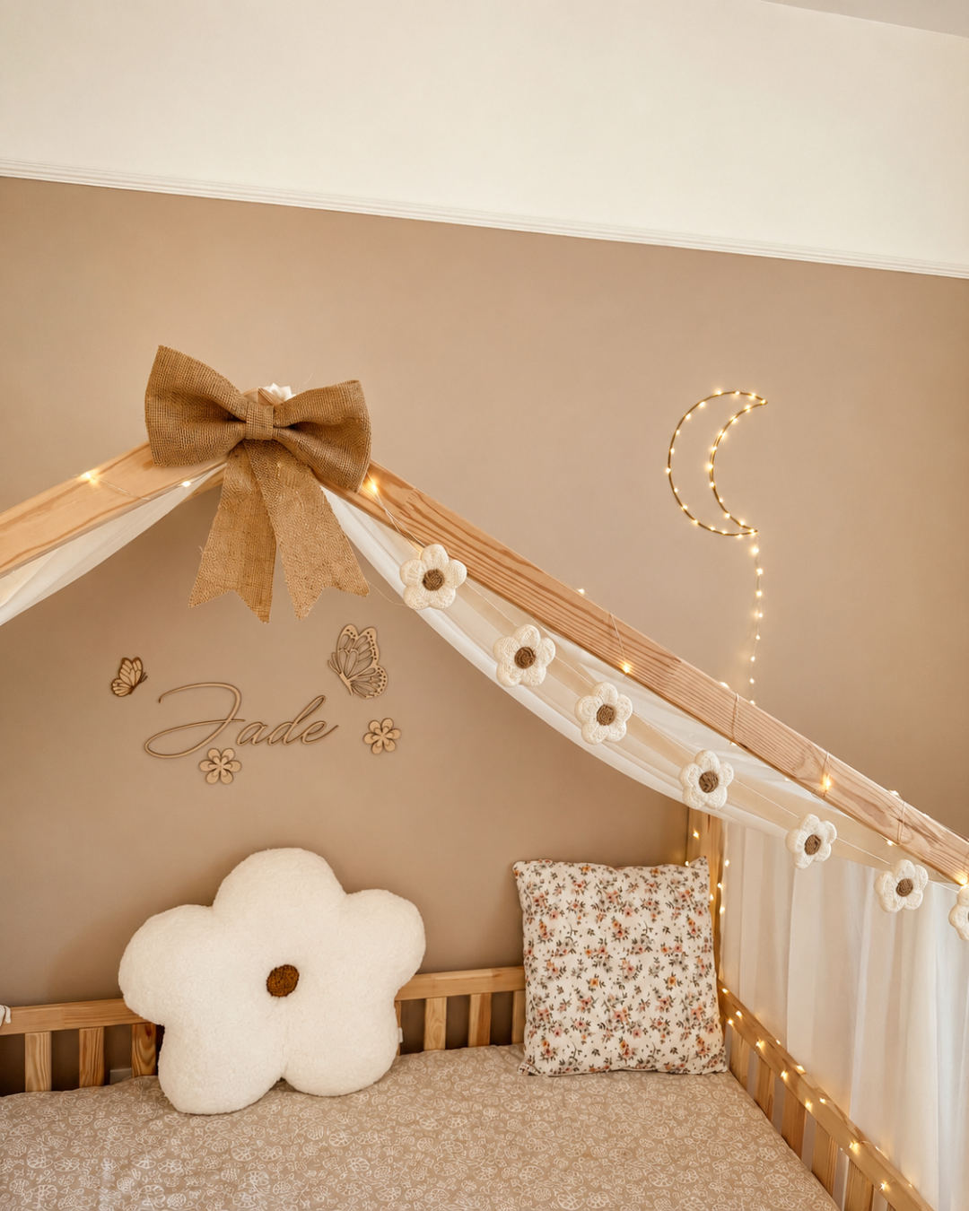 Guirlande de fleurs en laine feutrée installée sur un lit cabane dans une chambre d'enfant.
